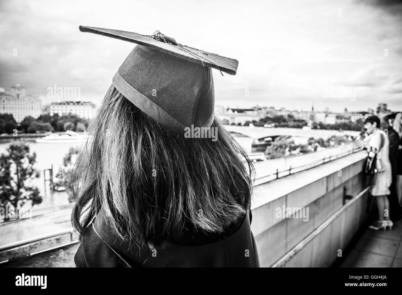 Abschlussfeiertag – ein junger Hochschulabsolvent mit Mortarboard blickt in die Zukunft der Royal Festival Hall, London, England, Großbritannien Stockfoto