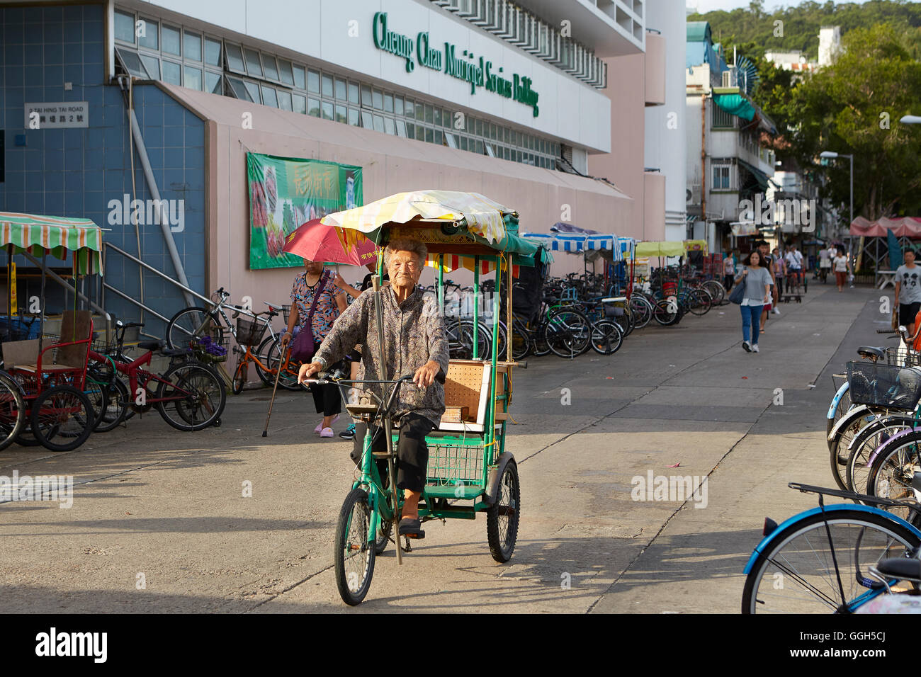 Eine alte chinesische Frau Zyklen hinter dem Markt In Cheung Chau, Hong Kong. Stockfoto