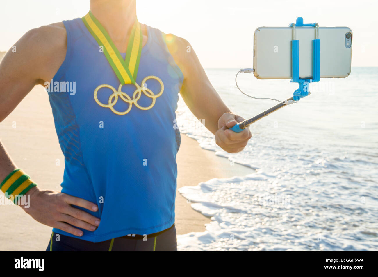 RIO DE JANEIRO - 10. März 2016: Sportler mit Olympischen Ringen Goldmedaille steht unter einem Selfie am Sonnenaufgang Strand. Stockfoto