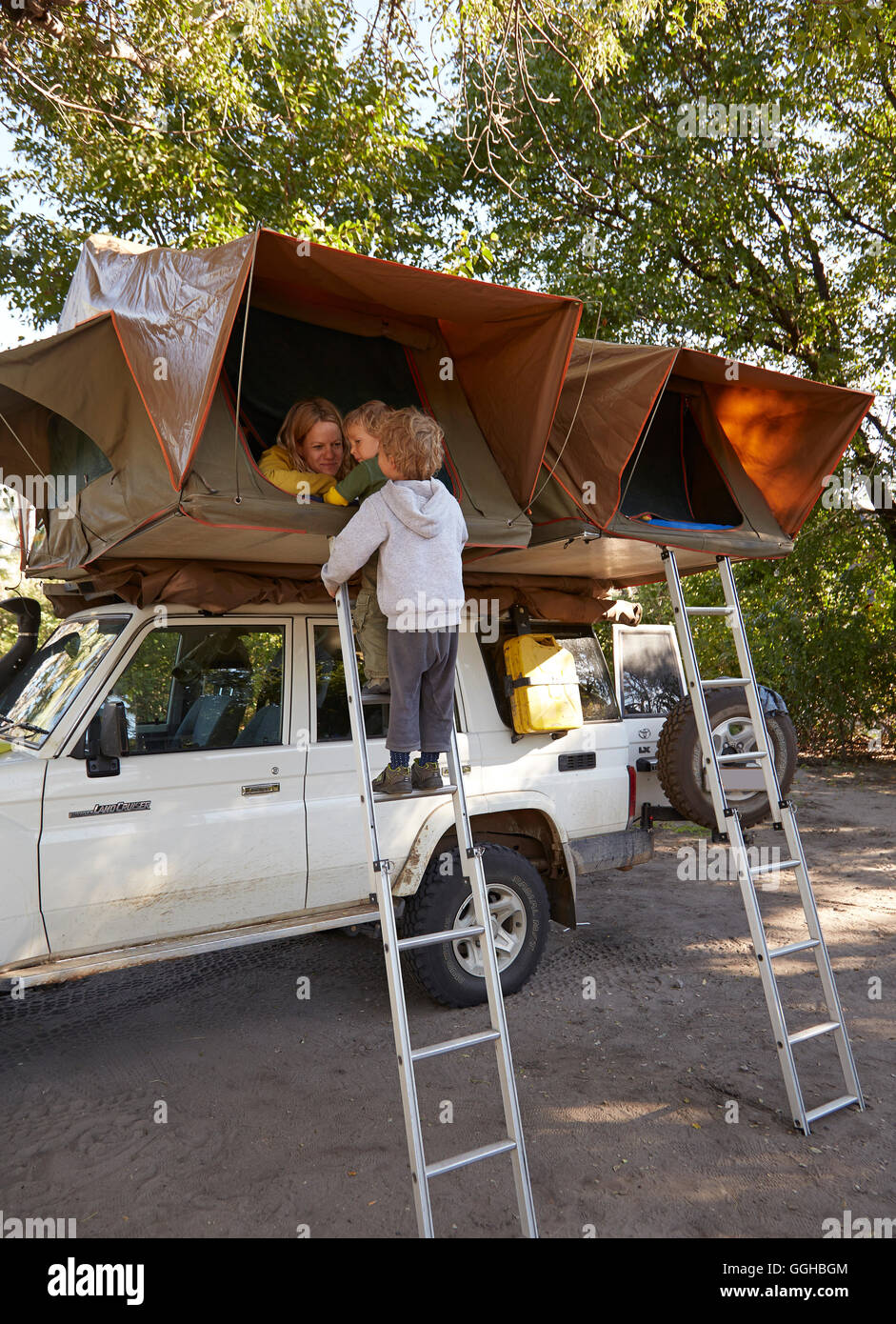 Jungs stehen auf einer Leiter, einem Dachzelt auf einen Geländewagen, Nata, Nxai Pan National Park, Botswana Stockfoto