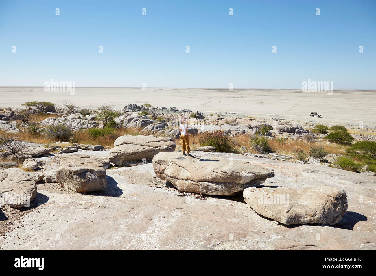 Frau steht auf einem Felsen bei der Suche über Salzwüste, Kubu Island, Makgadikgadi Pans Nationalpark, Botswana Stockfoto