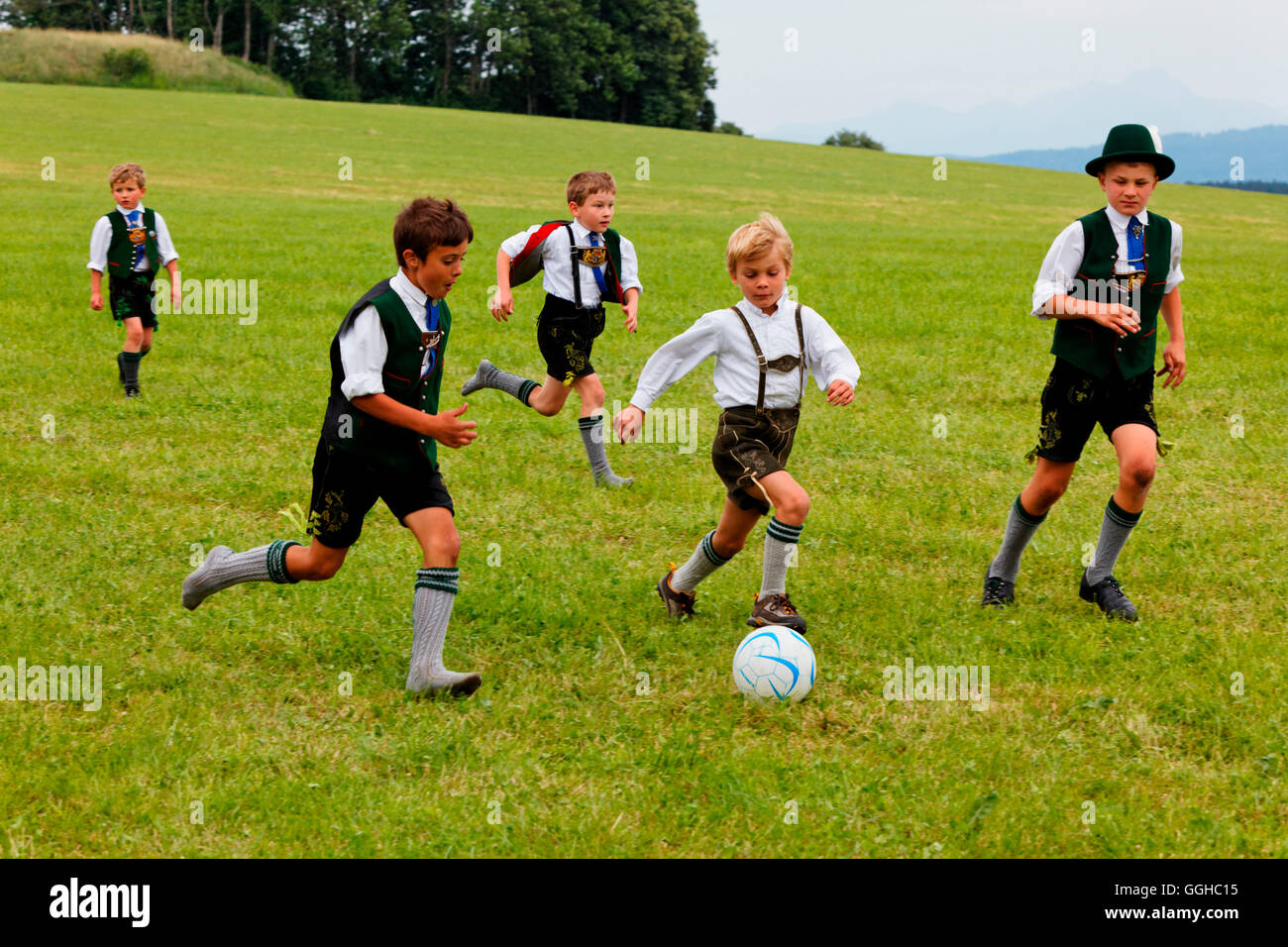 Kinder in traditionellen bayerischen verkleiden spielen Fußball, Jasberg, Dietramszell, Upper Bavaria, Bavaria, Germany Stockfoto