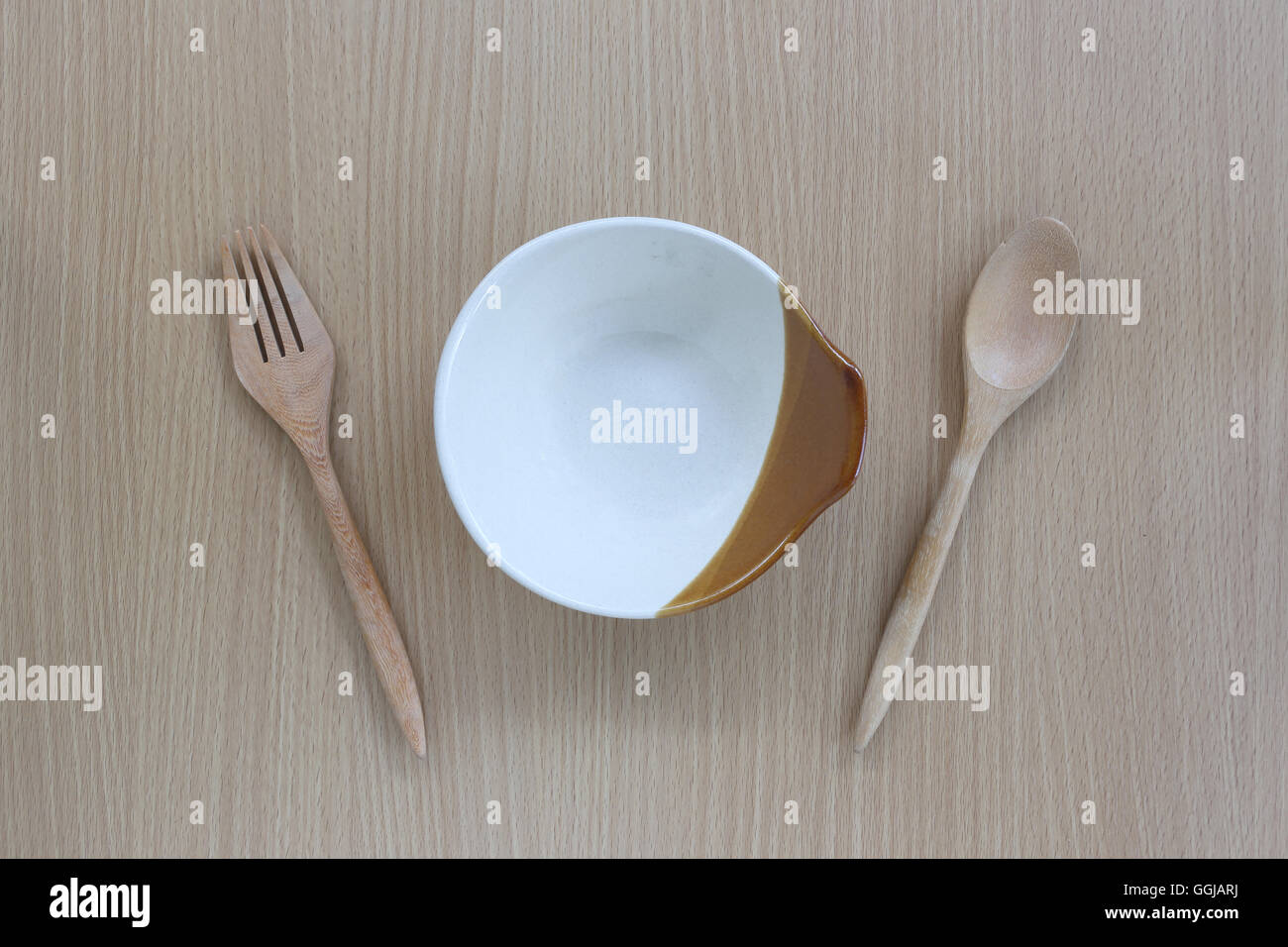Hölzerne Löffel, Gabel und Teller in der Draufsicht auf Holz Hintergrund für Design-Konzept Essen. Stockfoto