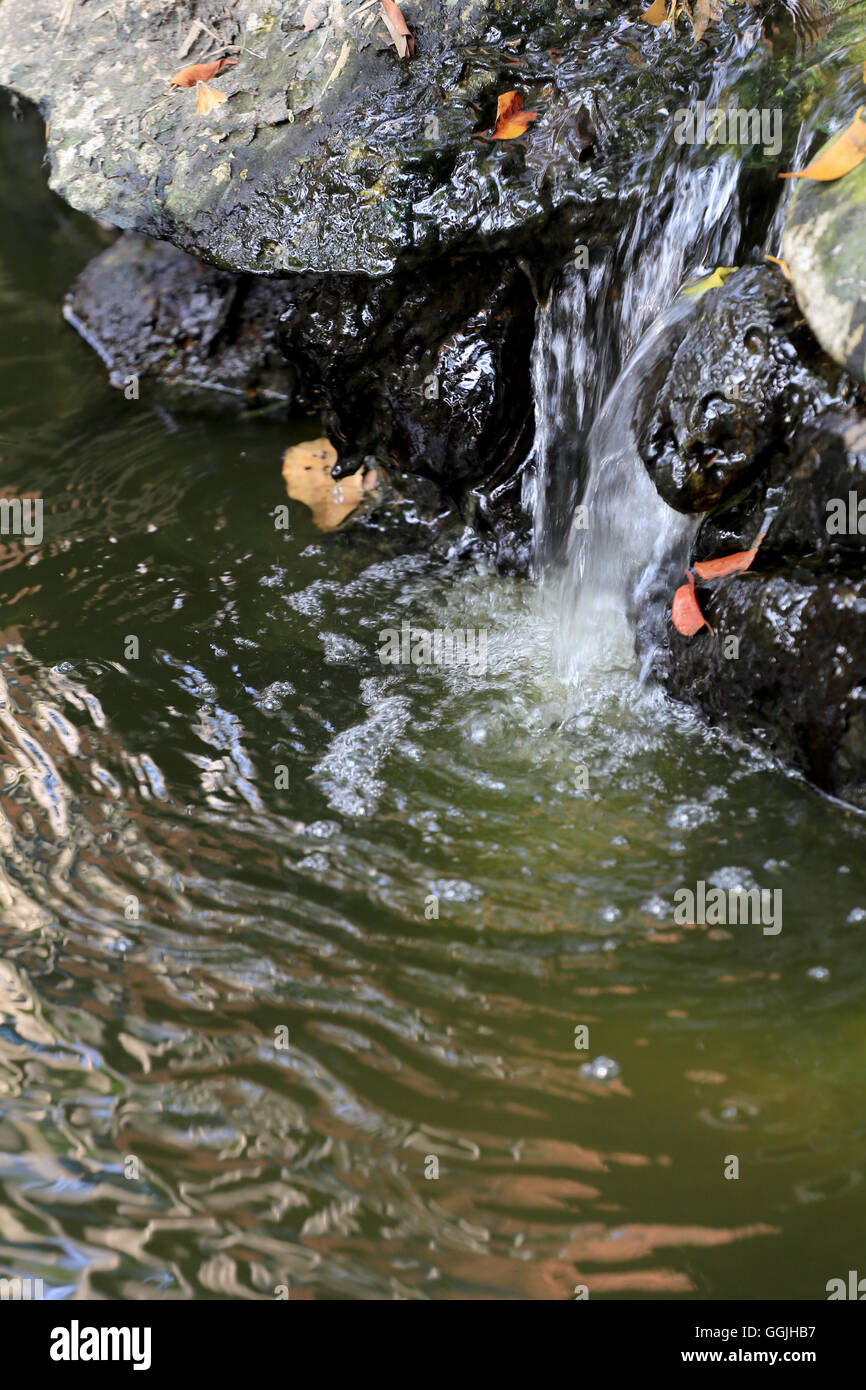 künstlicher Wasserfall aus Stein und Zement im öffentlichen Park und Wasser fließen. Stockfoto