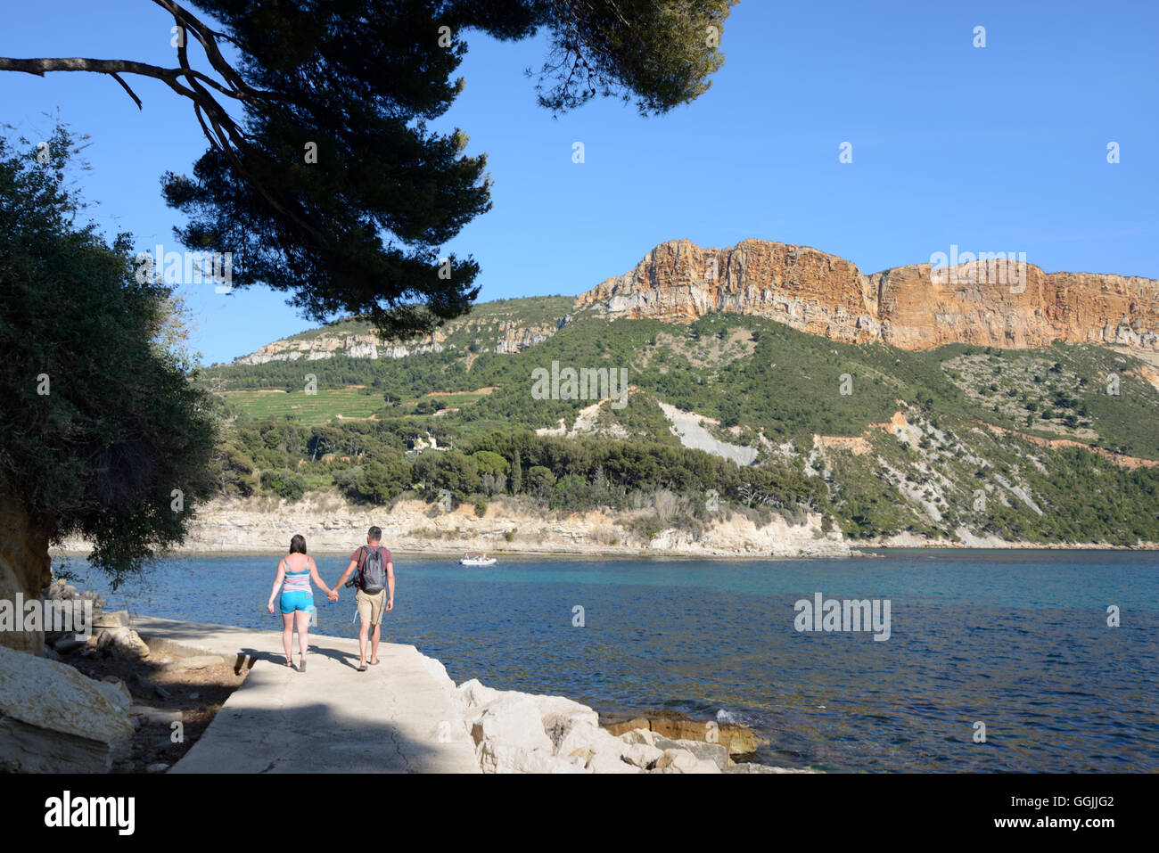 Junges Paar von Touristen gehen Hand in Hand entlang einer Küstenweg mit Cap Canaille & Klippen im Hintergrund Cassis Provence Stockfoto