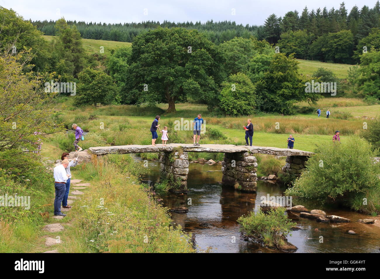 Menschen zu Fuß auf Postbridge Clapper Bridge, Dartmoor, Großbritannien Stockfoto