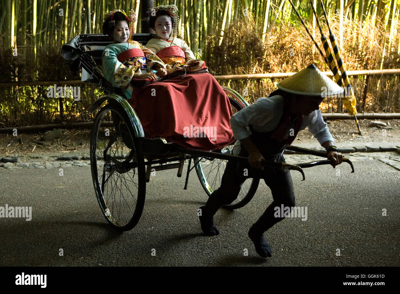 Zwei junge Geisha-Frauen durch einen Bambuswald von Ricksha, Kyoto, Kansai Region, Japan gezogen wird Stockfoto