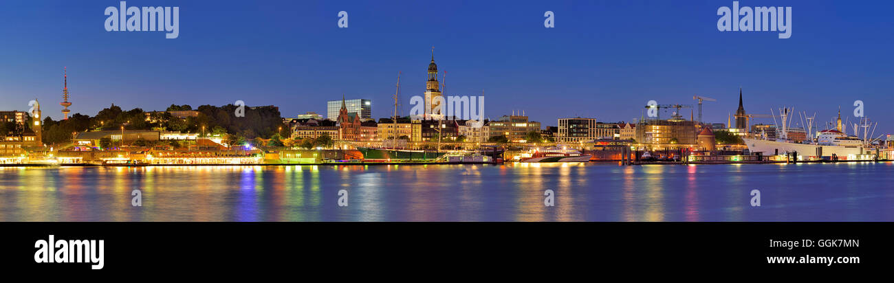 Panorama von Hamburg mit Blick über die Elbe zu beleuchteten St. Pauli-Landungsbrücken mit Wolkenkratzer, Pegelturm, Heinrich Stockfoto