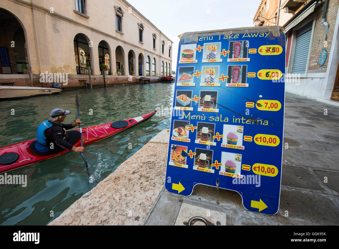 Mann paddeln vorbei an einem Fast-Food-Menü, Murano, Venedig, Italien Stockfoto