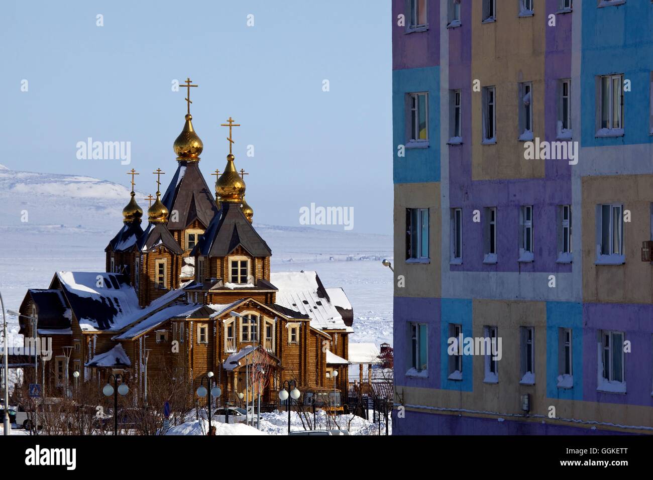 Orthodoxe Kathedrale der Heiligen Dreifaltigkeit neben farbigen Apartmenthaus, Anadyr, Chukotka autonomes Okrug, Sibirien, Russland Stockfoto