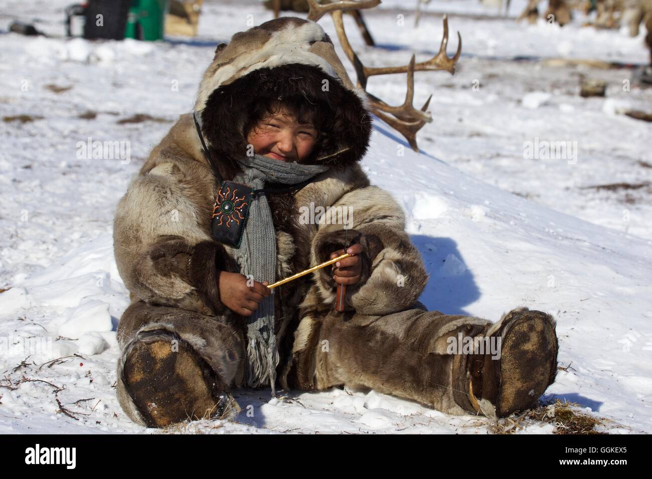 Nomad Mädchen gekleidet in Rentierfelle, sitzen in den Schnee, Chukotka autonomes Okrug, Sibirien, Russland Stockfoto