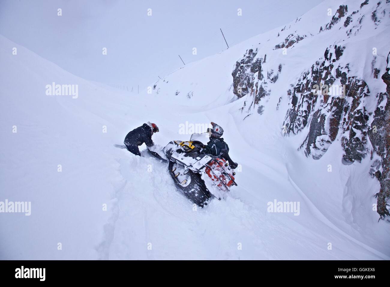 zwei Männer Baggern ein Schneemobil, die steckte im Tiefschnee, Chukotka autonomes Okrug, Sibirien, Russland Stockfoto