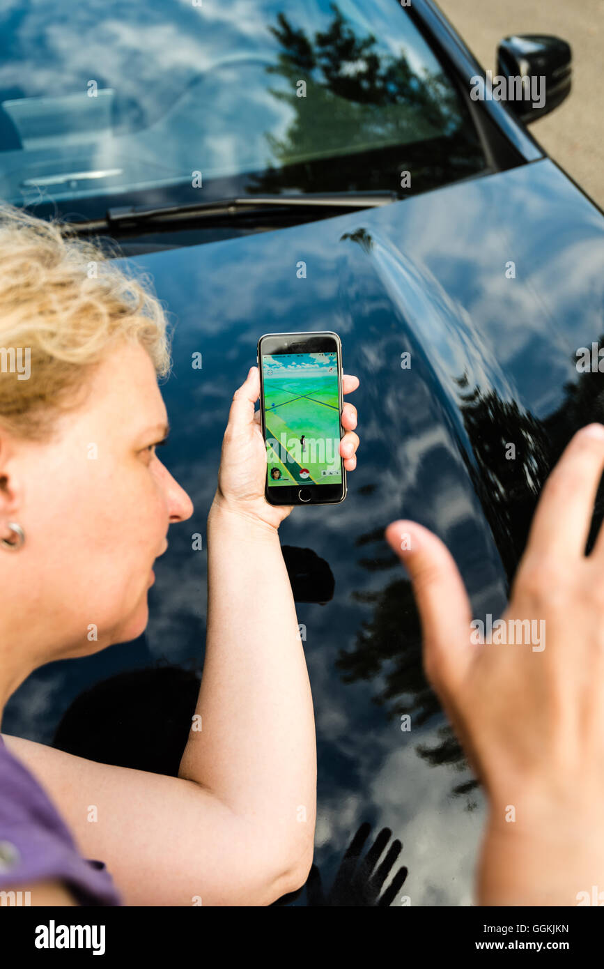 Ostfildern, Deutschland - 17. Juli 2016: Eine Frau spielen Pokemon unterwegs auf ihrem Smartphone von einem Auto beim achtlos überqueren angefahren wird die Stockfoto