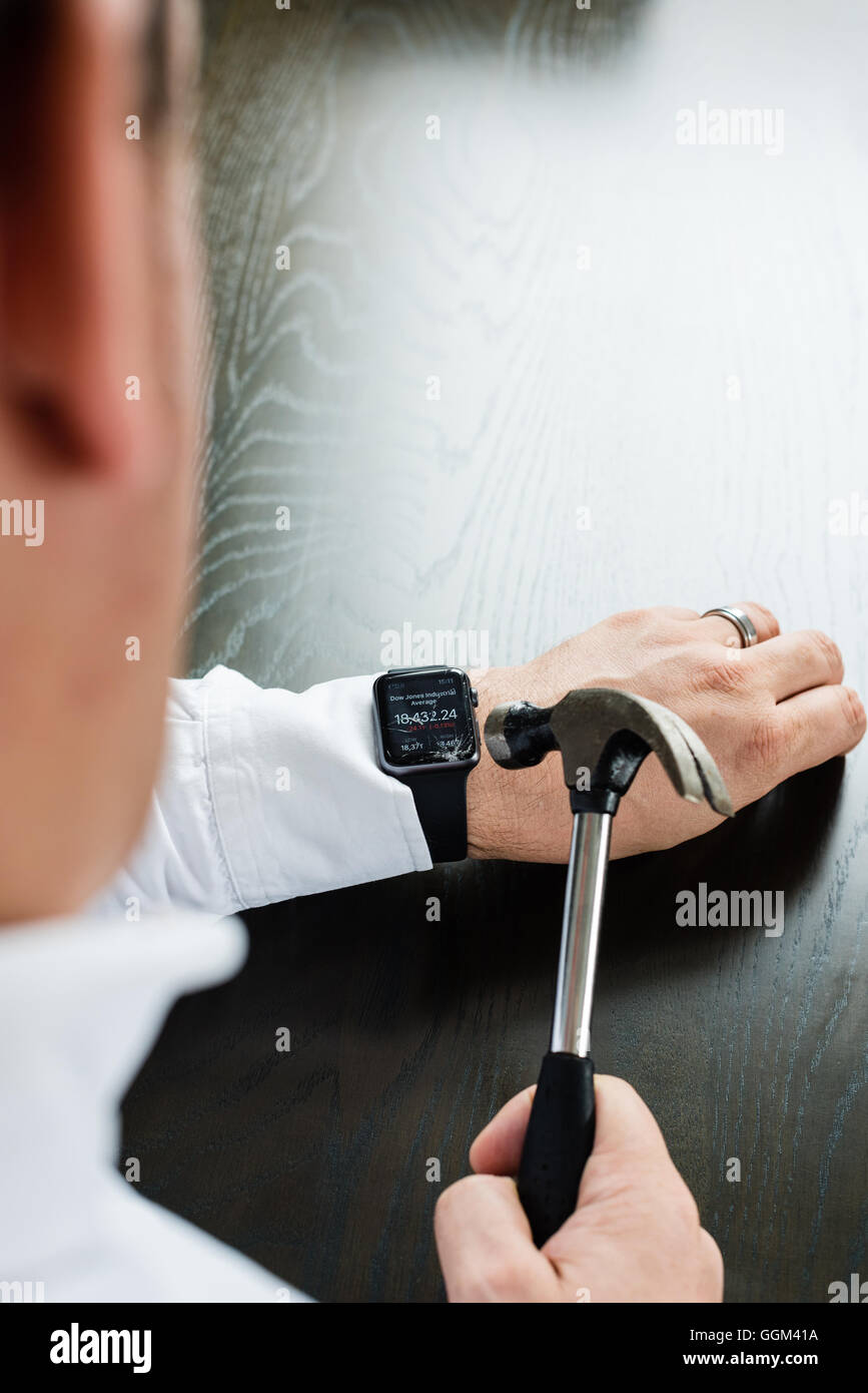 Ostfildern, Deutschland - 31. Juli 2016: Ein Geschäftsmann trägt ein weißes Hemd ist die Apple Watch am Handgelenk mit einem Hamm zu zerstören Stockfoto