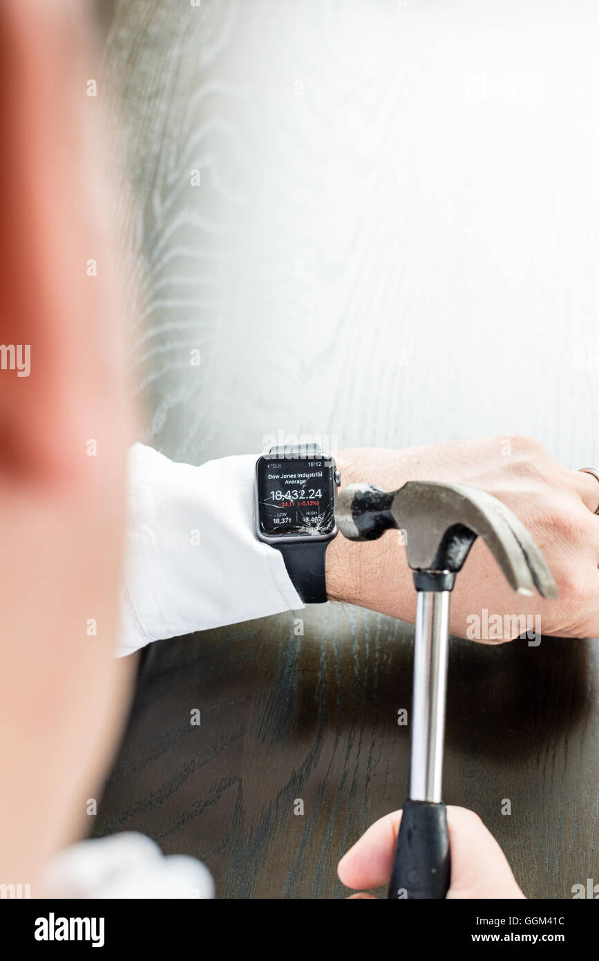 Ostfildern, Deutschland - 31. Juli 2016: Ein Geschäftsmann trägt ein weißes Hemd ist die Apple Watch am Handgelenk mit einem Hamm zu zerstören Stockfoto