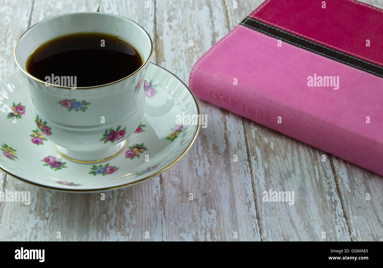 Ein rosa Bibel auf einem Holzbrett-Brett mit einer Tasse Kaffee oder Tee bereit für ein Bibelstudium Stockfoto