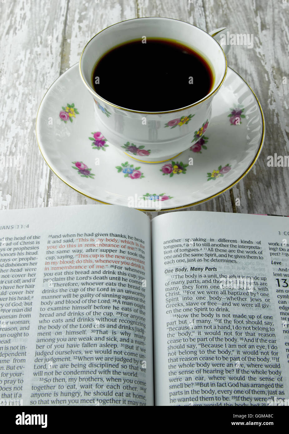 Die Heilige Bibel eröffnet mit einer Tasse Kaffee oder Tee auf einem Holzbrett-Hintergrund Stockfoto