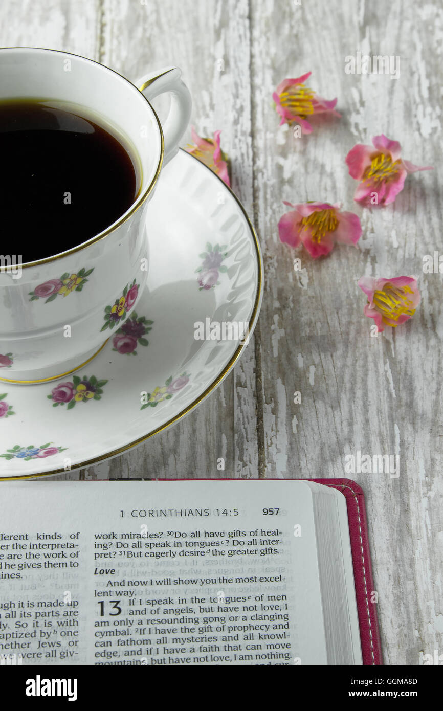 Die Bibel, das Buch der Korinther mit einer Tasse Kaffee oder Tee auf einem Holzbrett Hintergrund geöffnet Stockfoto