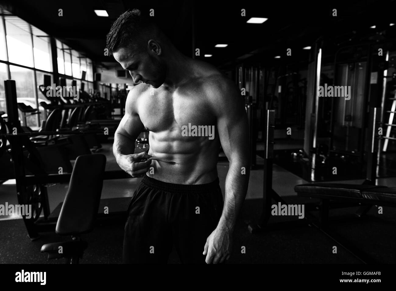 Porträt einer jungen Mann Maßnahme sein Körperfett am Bauch In ein Fitness-Studio Stockfoto