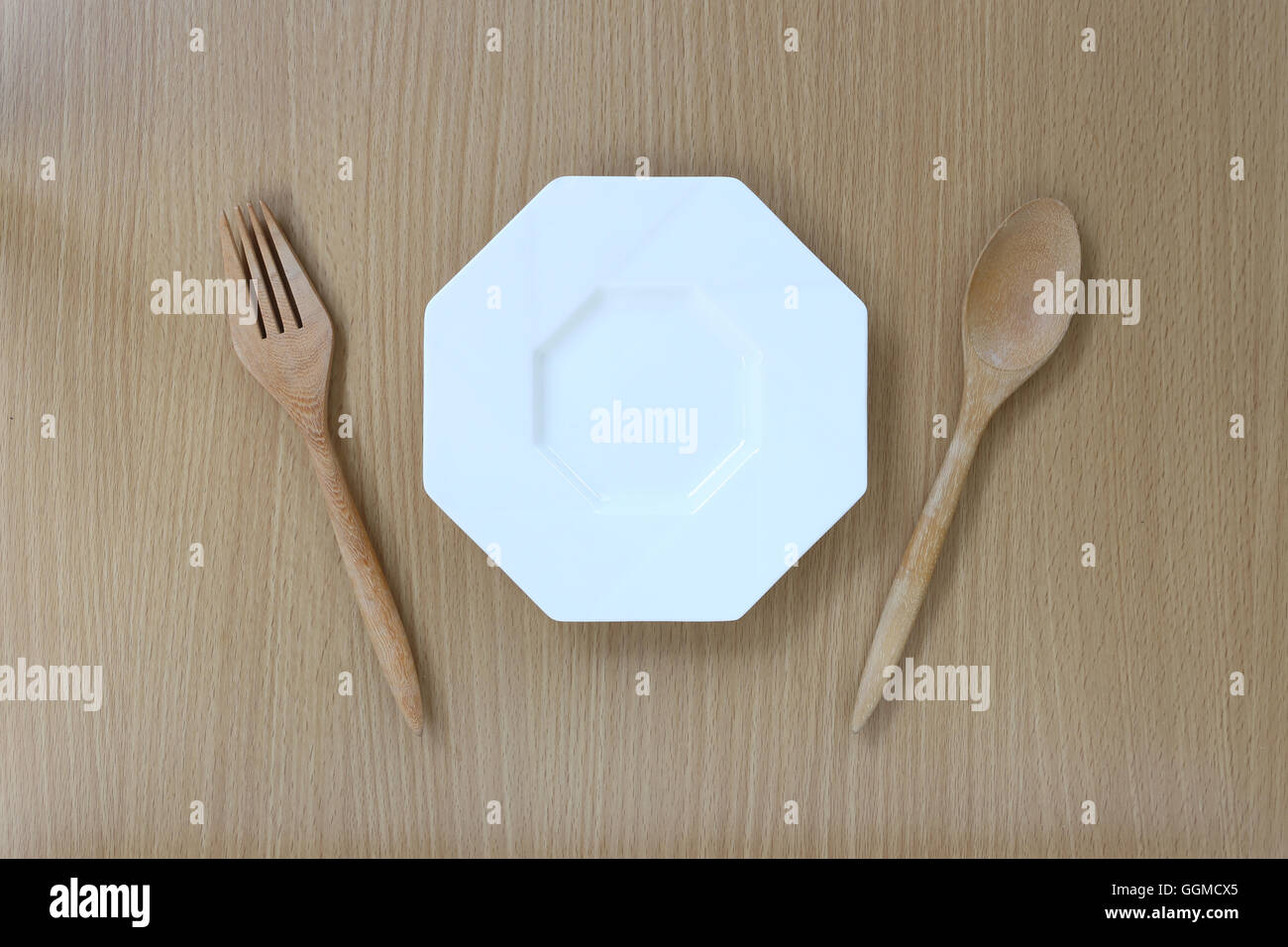 Hölzerne Löffel, Gabel und Teller in der Draufsicht auf Holz Hintergrund für Design-Konzept Essen. Stockfoto