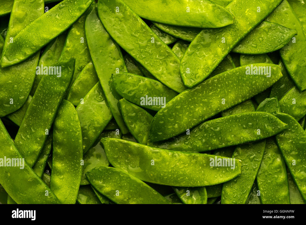 Haufen von nassen grünen Erbsen in Hülsen Stockfoto
