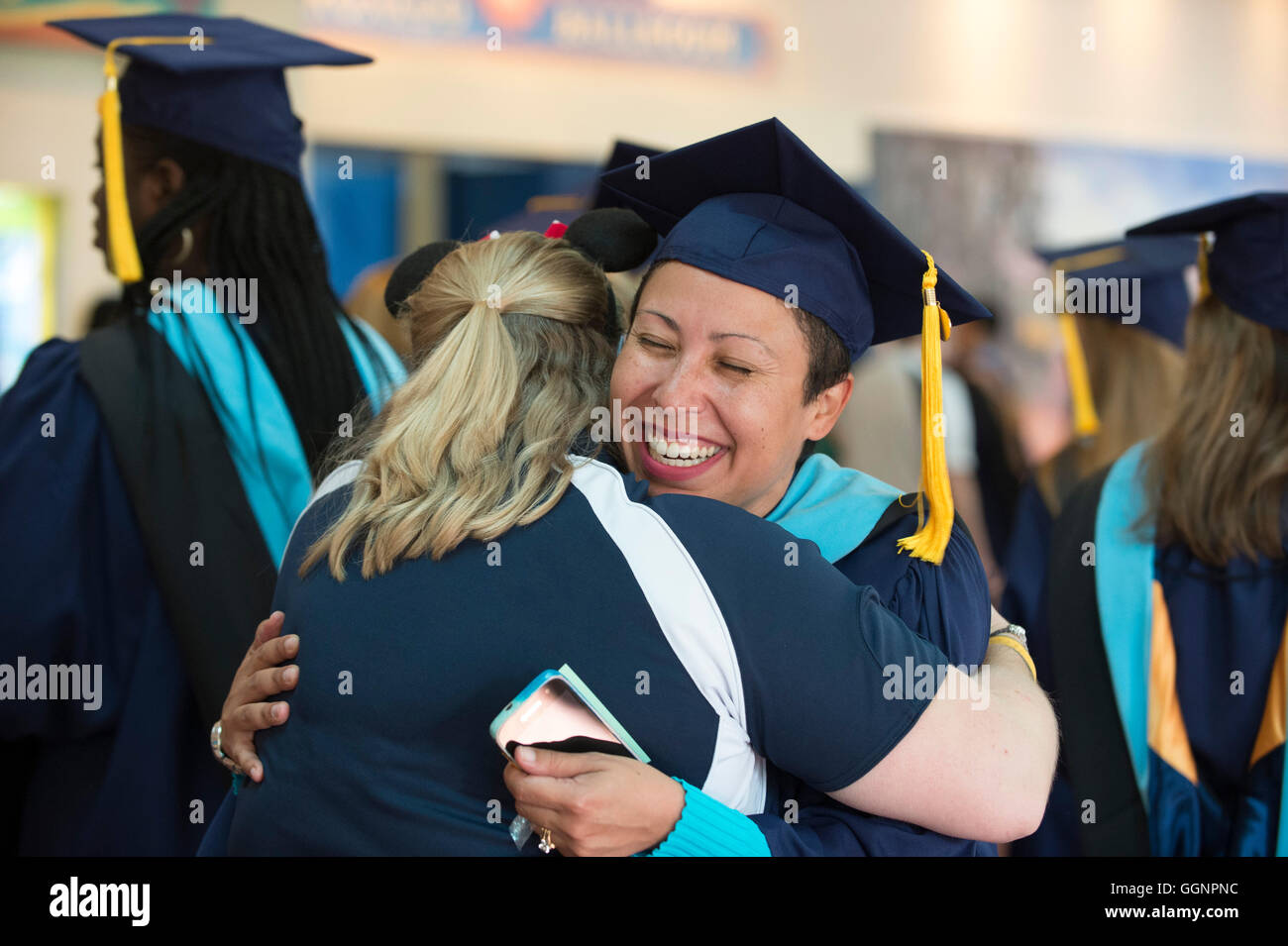 Absolvent der Universität Western Governors bekommt Umarmung von Freund nach der Abschlussfeier in Orlando, Florida. Stockfoto