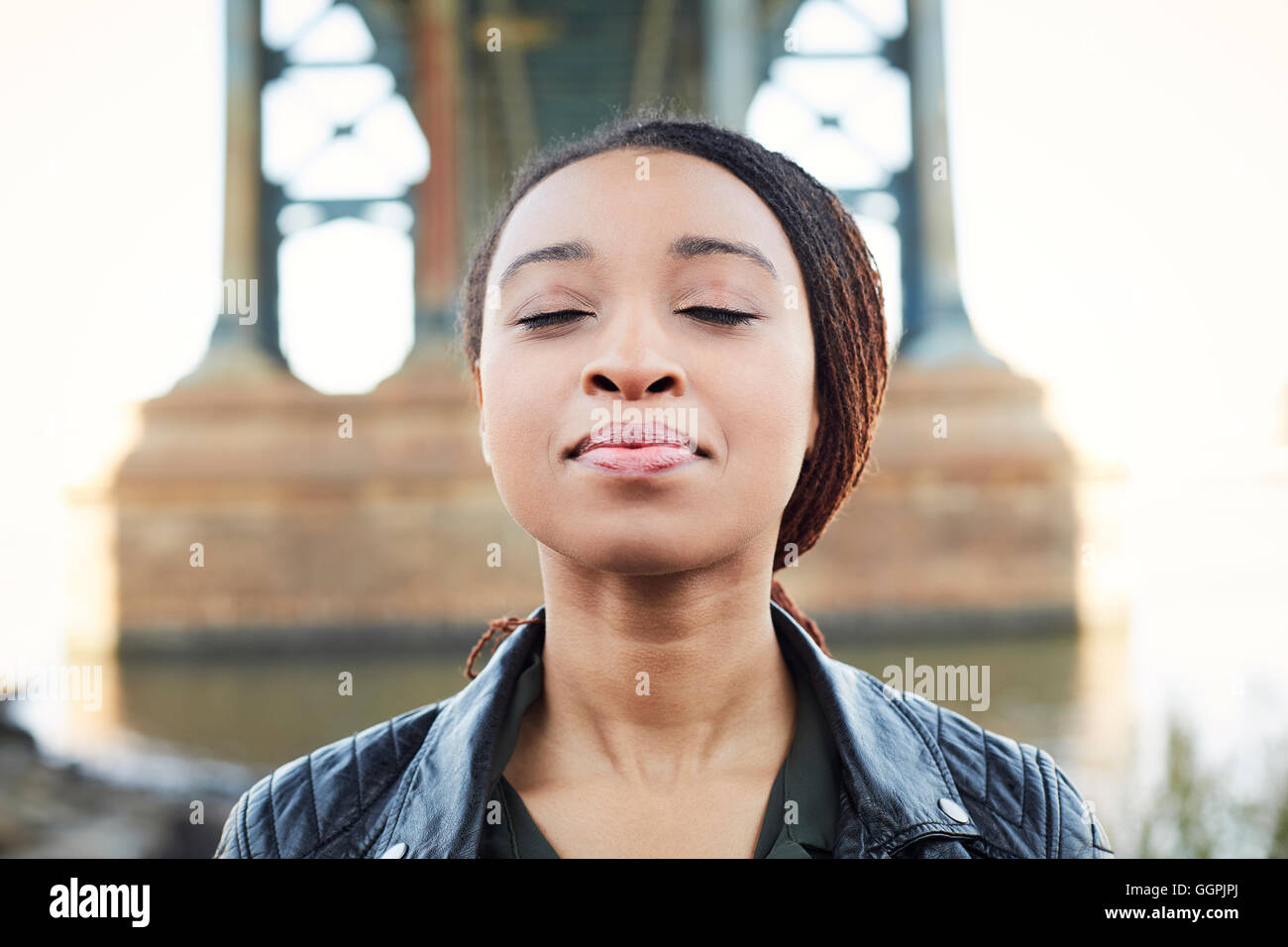Schwarze Frau mit Augen geschlossen an der Brücke denken Stockfoto