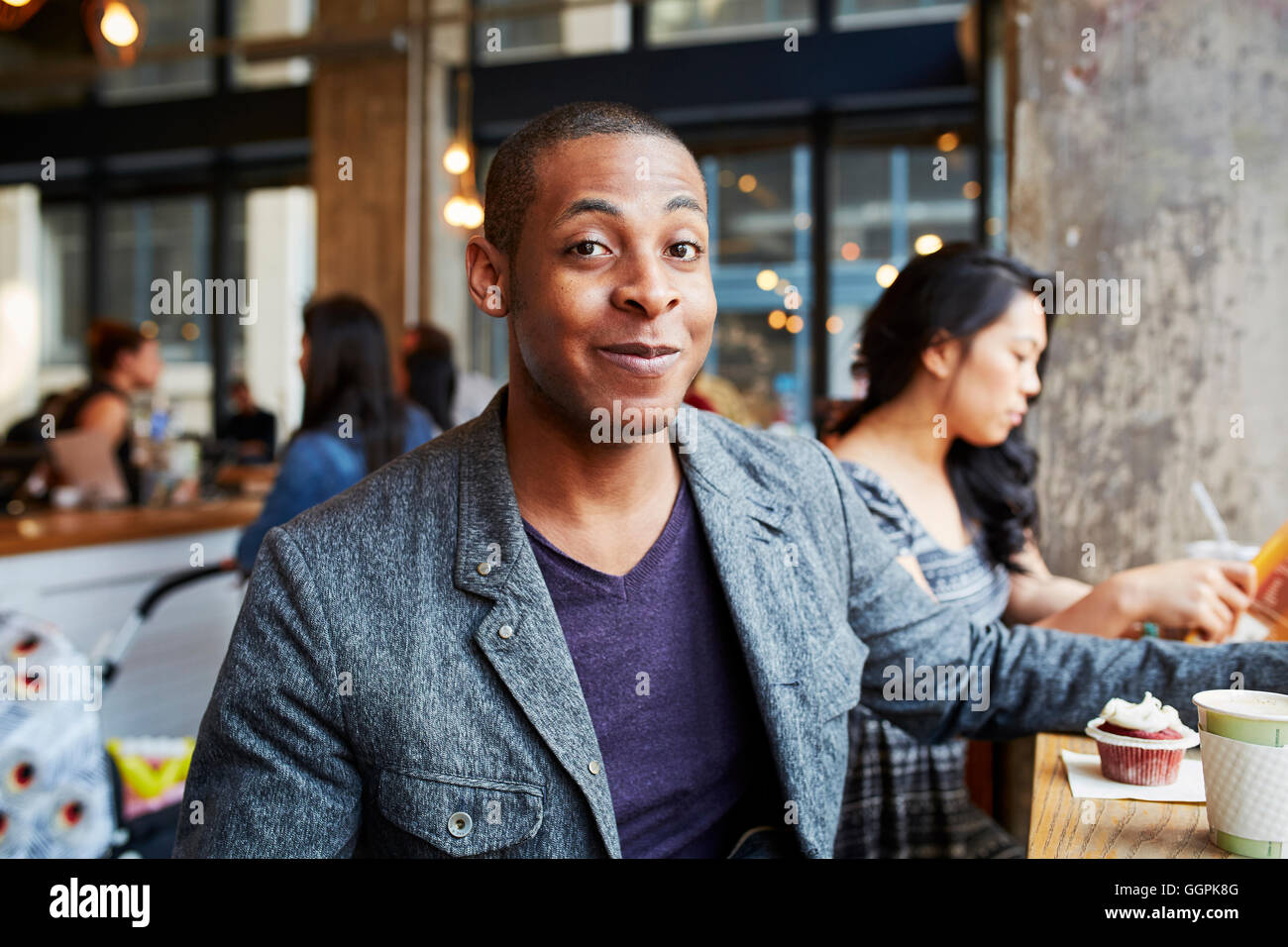 Lächelnder Mann mit Kaffee und Kuchen im Café Stockfoto