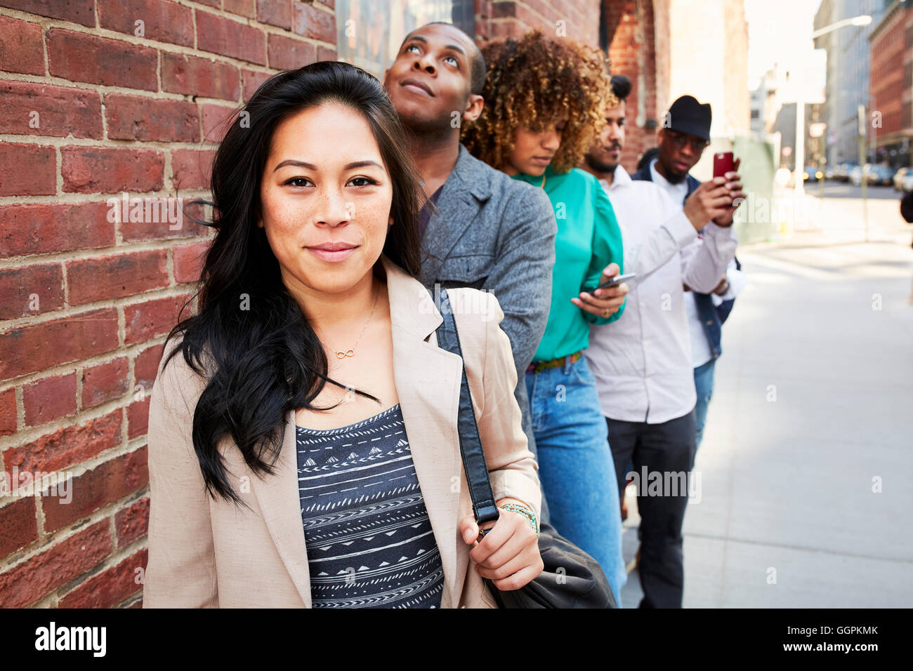 Menschen in der Schlange warten auf Bürgersteig mit Handys Stockfoto