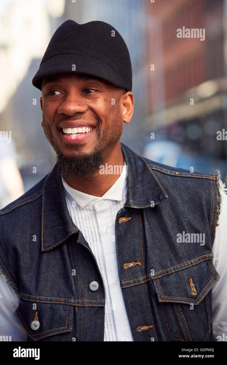 Lächelnder afroamerikanische Mann mit Hut und Denim Weste Stockfoto