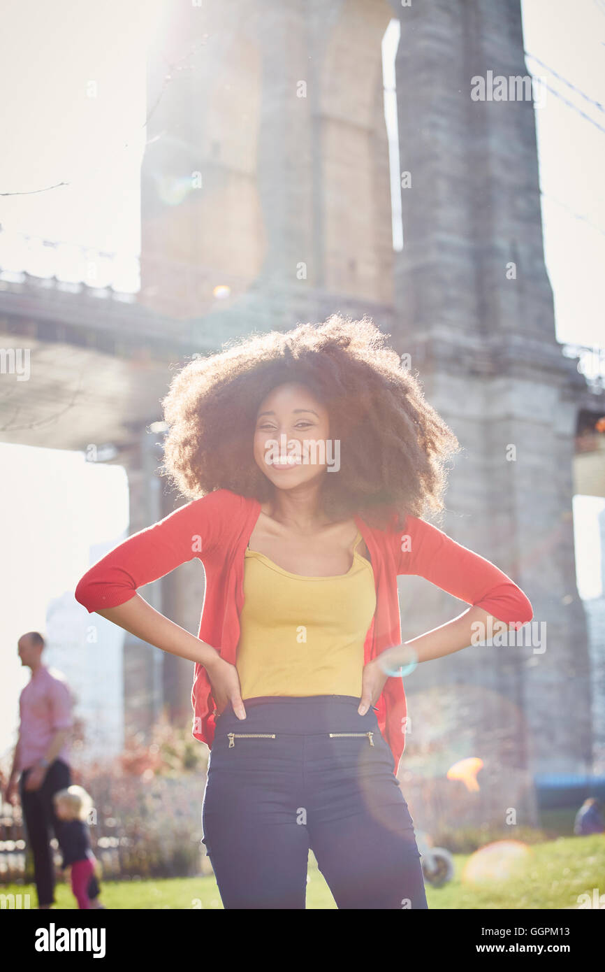 Lächelnde schwarze Frau posiert mit Hände auf den Hüften Stockfoto