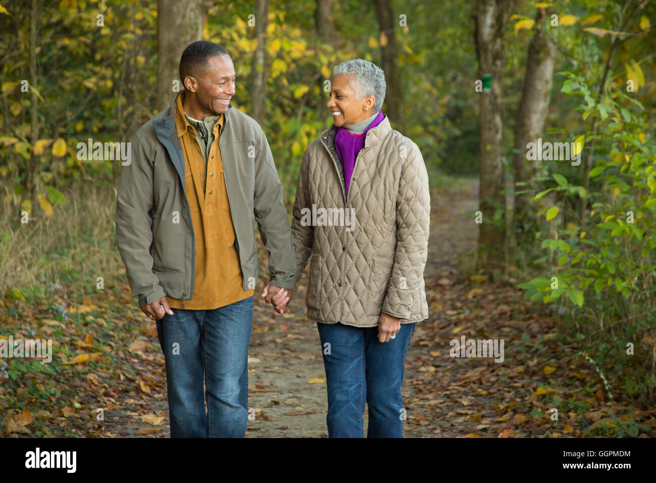 Älteres Paar Hand in Hand spazieren im Wald Stockfoto