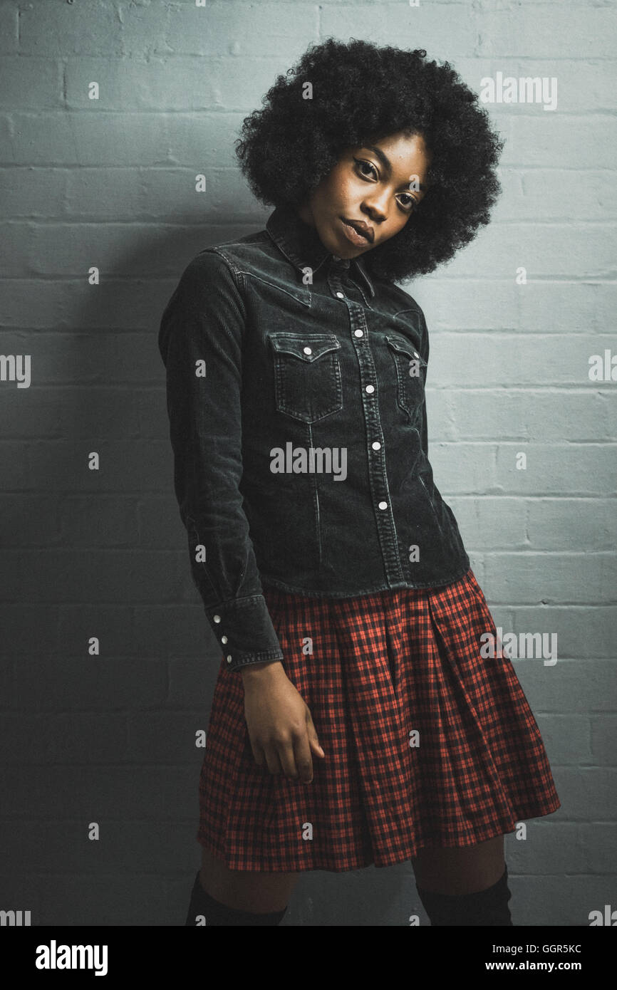 Die junge Afro Caribbean-Frau in schwarzem Denim-Hemd posiert für ein Fashion-Shooting Stockfoto