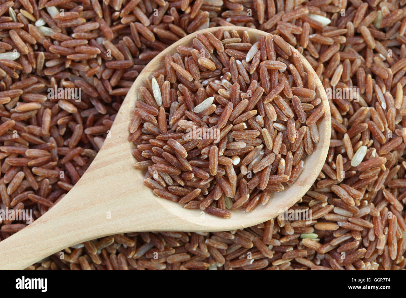 Bio Naturreis in Holzlöffel auf Haufen Reis für Natur Essen Hintergrund. Stockfoto