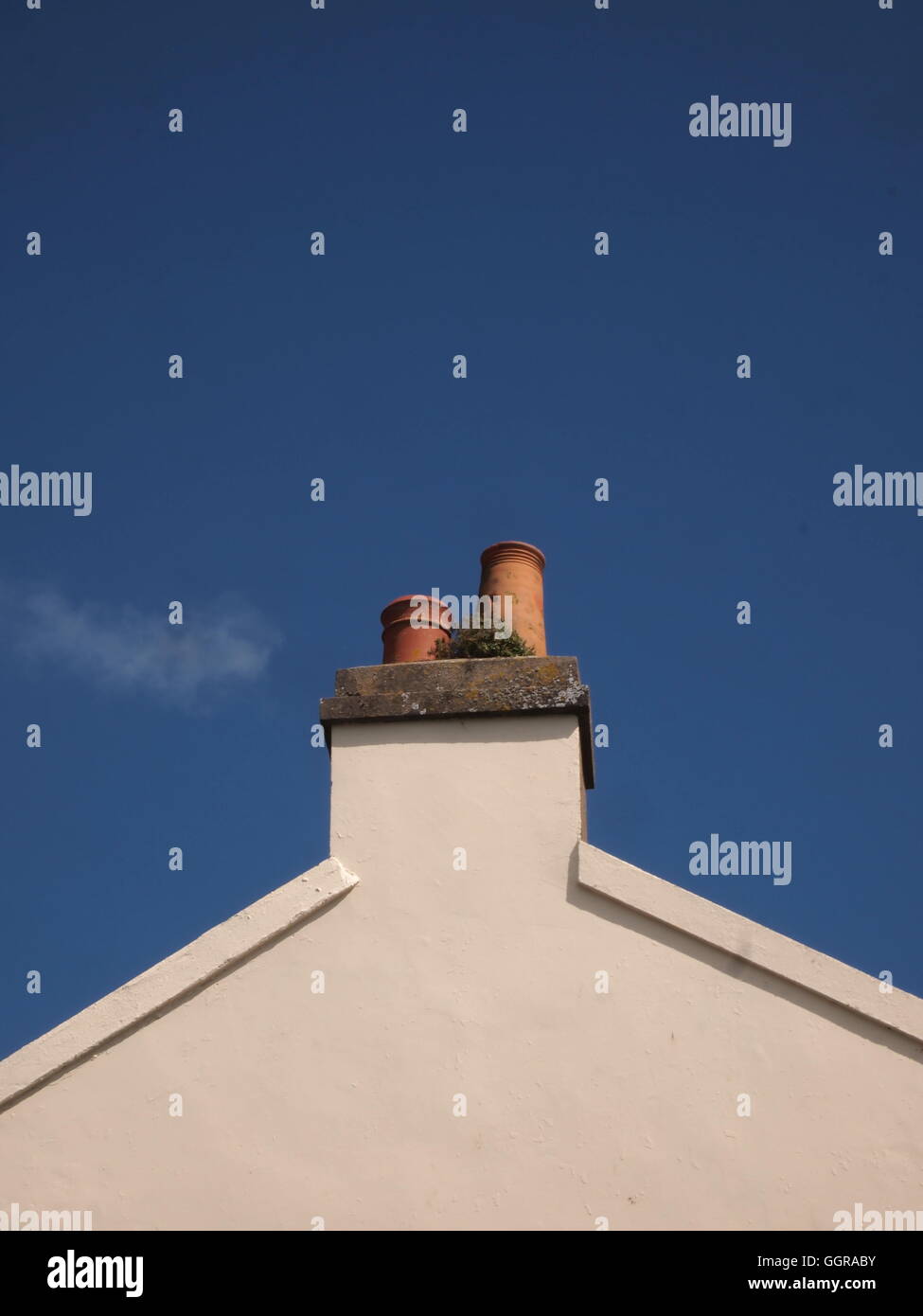 weiße Ende eines Gebäudes und Dach mit Kaminen und einem tiefblauen Hintergrund Himmel Stockfoto