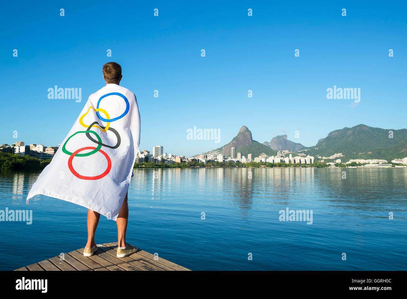 RIO DE JANEIRO - 27. März 2016: Athlet steht in der Olympischen Flagge vor Lagoa Rodrigo da Freitas Lagune drapiert. Stockfoto