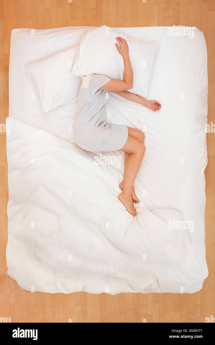 Mitte Erwachsene Frau liegen im Bett mit Kissen über den Kopf. Stockfoto