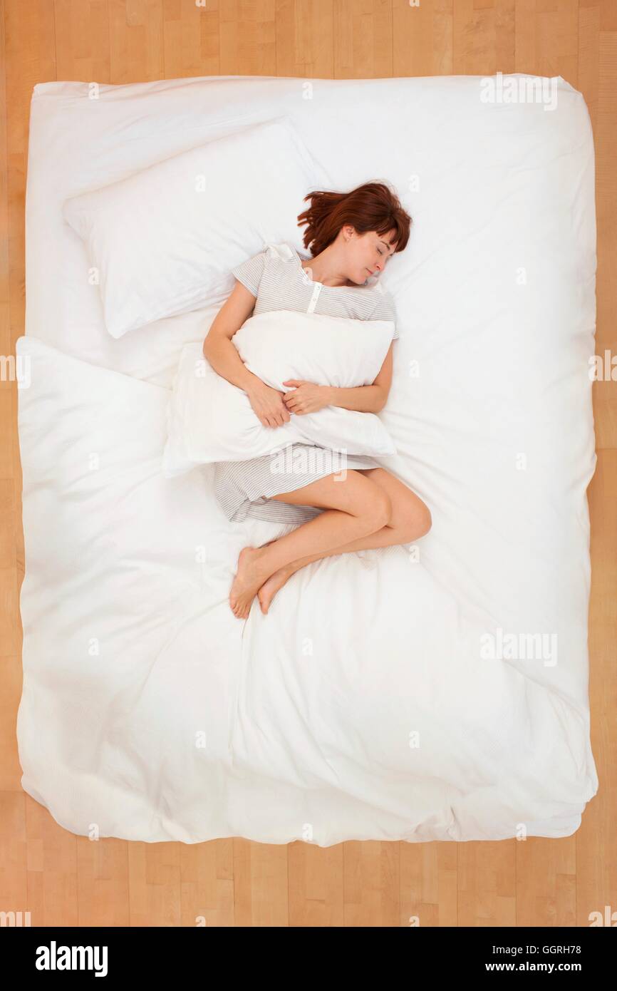 Mitte Erwachsene Frau im Bett mit Kissen liegend. Stockfoto