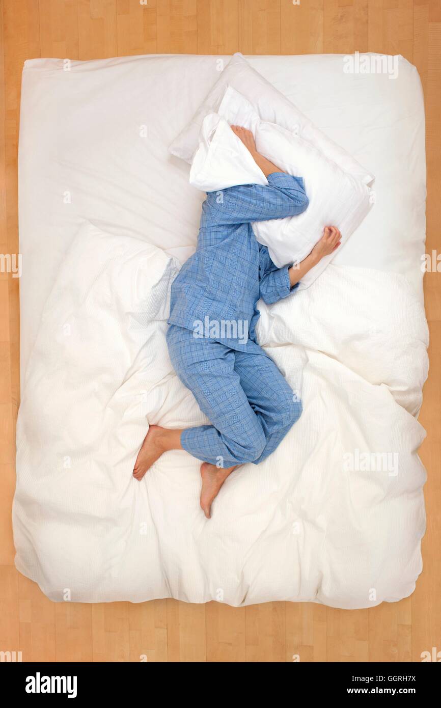 Mitte Erwachsene Frau liegen im Bett mit Kissen über den Kopf. Stockfoto
