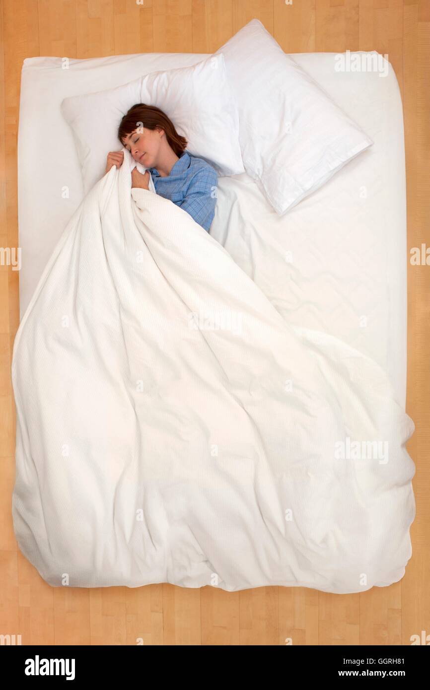 Mitte Erwachsene Frau im Bett Bettdecke halten. Stockfoto