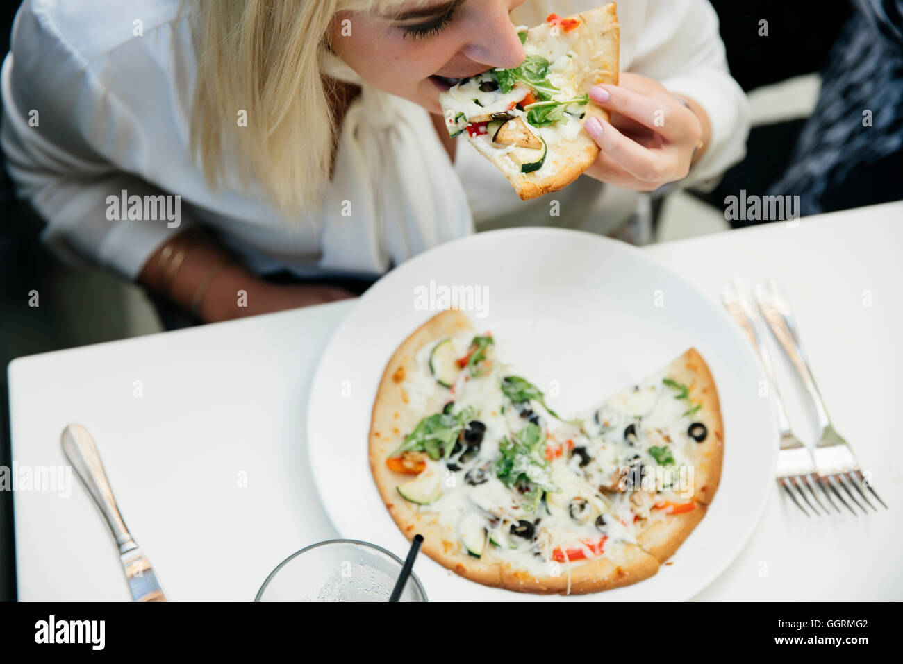 Kaukasische Frau Essen Stück Pizza im restaurant Stockfoto