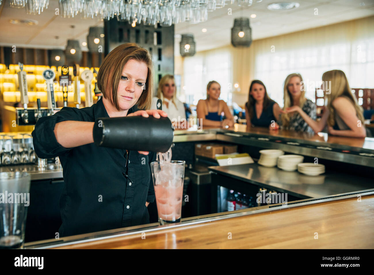 Kaukasische Barkeeper cocktail aus Mischer in Glas gießen Stockfoto