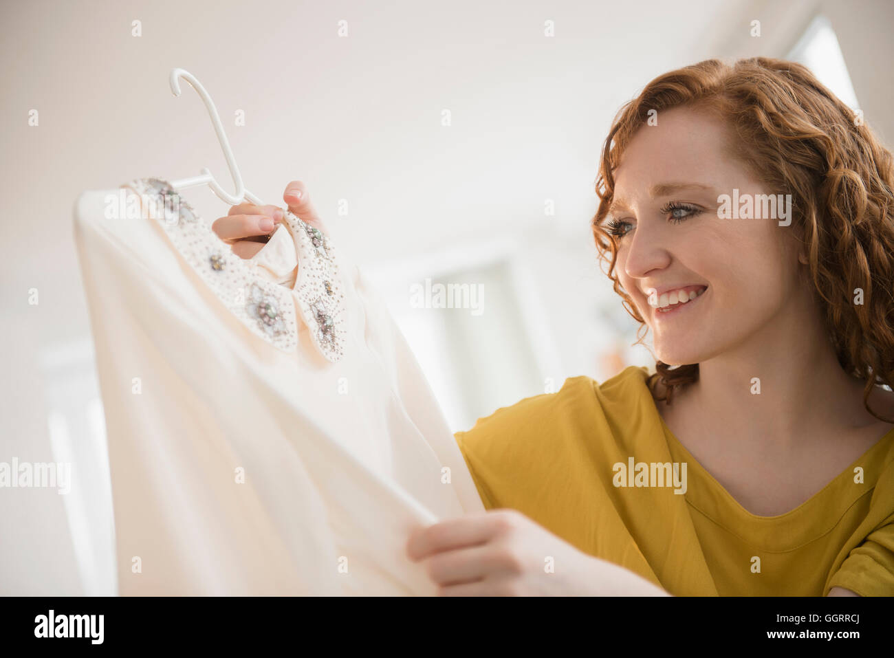Lächelnd kaukasischen Frau Holding Bluse auf Kleiderbügel Stockfoto