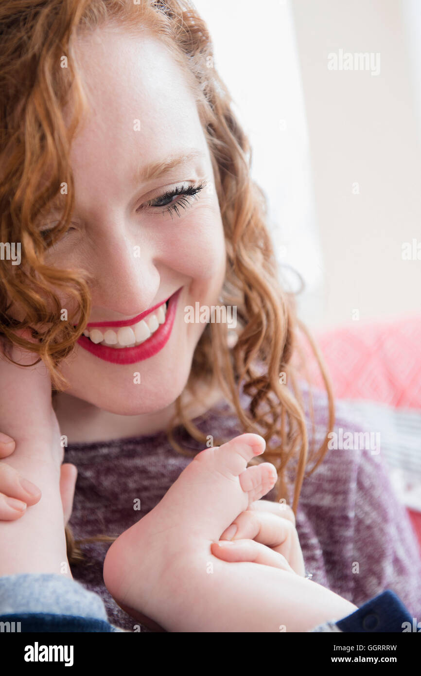 Kaukasische Frau hält Fuße des Baby Sohn Stockfoto