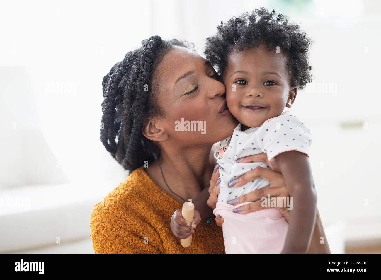 Lächelnde schwarze Mutter Tochter auf Wange küssen Stockfoto