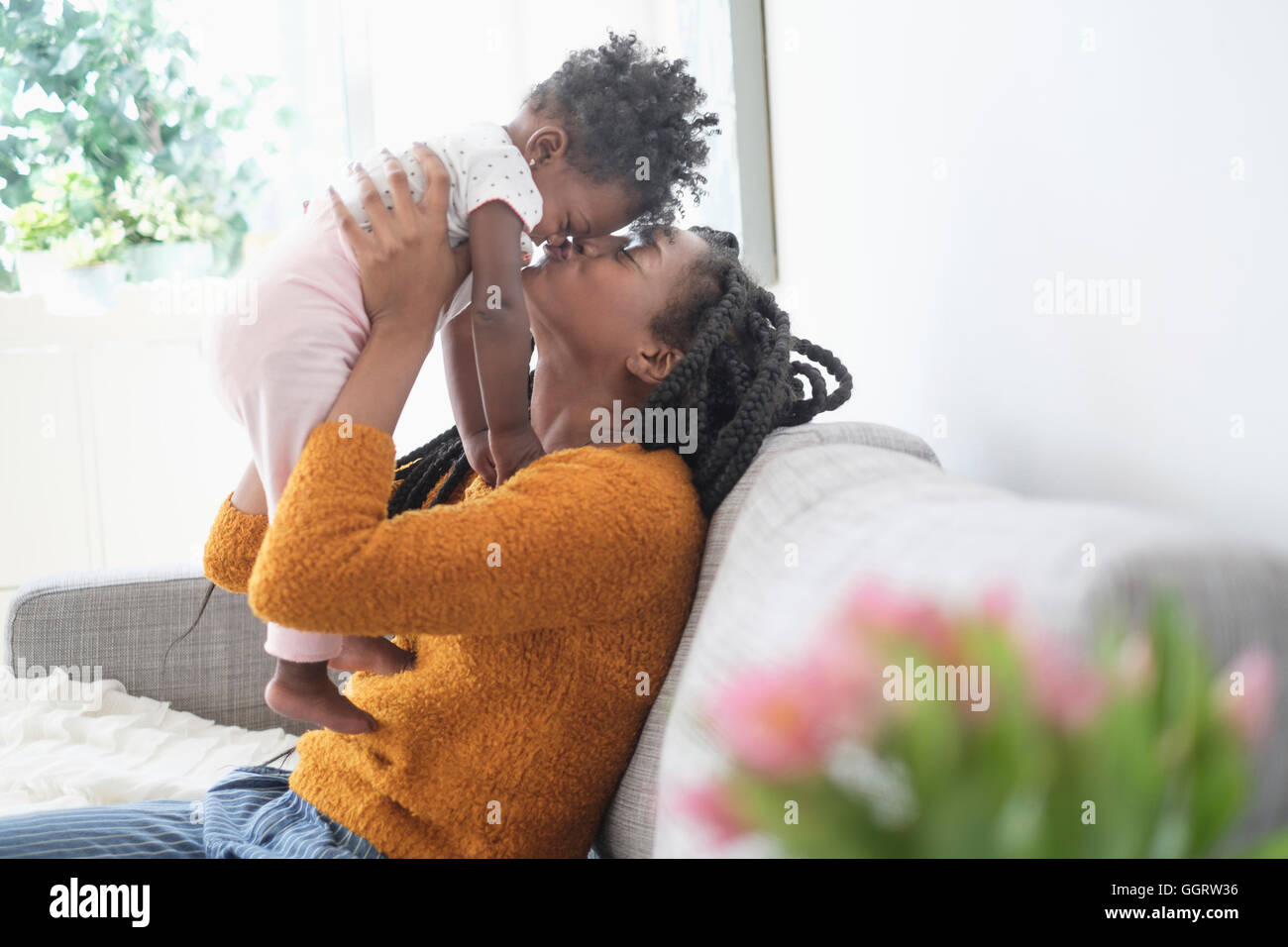 Schwarze Frau küssen Nase Tochter auf sofa Stockfoto