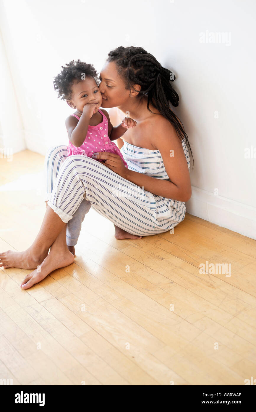 Schwarze Frau sitzen auf Boden küssen Wange Tochter Stockfoto