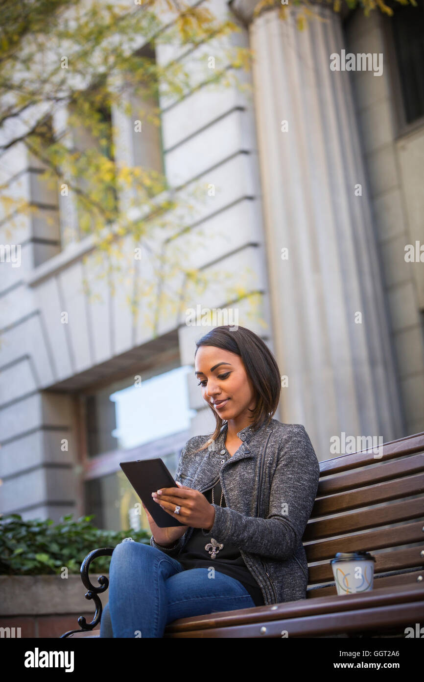 Indische Frau sitzen auf Stadt-Bank mit digital-Tablette Stockfoto