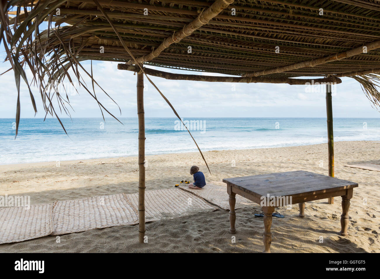 Kaukasische Junge sitzt auf Matte am Strand Stockfoto