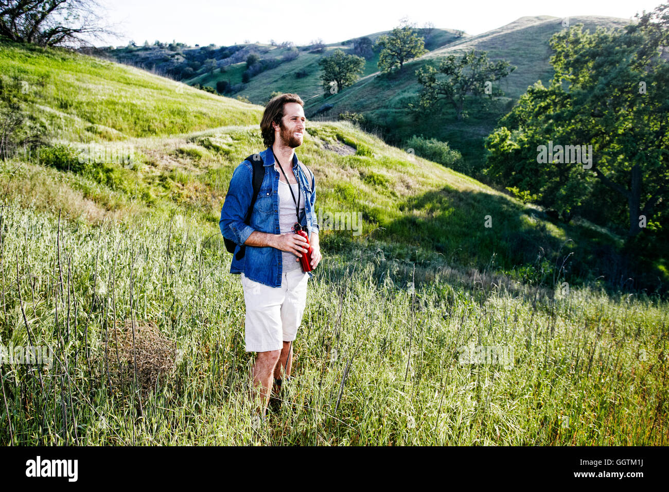 Kaukasische Wanderer stehend Gras am Berg halten Wasser Flasche Stockfoto